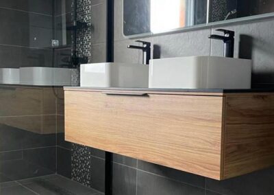 Lavabo double avec miroirs ovales sur mur en béton et armoire